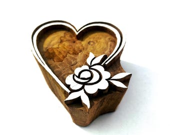 May include: A heart-shaped wooden block with a white outline and a carved white rose design. The block is made of brown wood and is used for printing or stamping. The rose has detailed petals and leaves.
