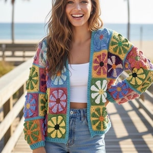 May include: A vibrant, open-front crochet cardigan with a floral design. The jacket showcases a patchwork pattern with diverse flower motifs in shades of blue, yellow, pink, and green. The cardigan is worn over a white top and denim shorts.