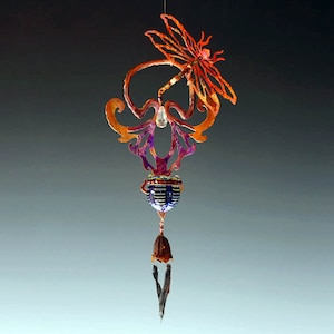 May include: A colorful metal mobile with a dragonfly design, a crystal, and a bell. The mobile is suspended from a string and has a purple, blue, and orange color scheme.