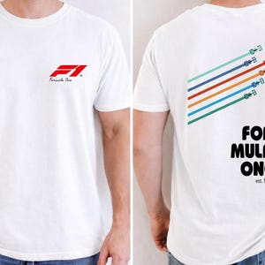 Pu&ograve; includere: Una t-shirt bianca a maniche corte con il logo rosso Formula 1 sul petto. Il retro mostra una grafica di cinque auto da corsa colorate in formazione diagonale sopra il testo FORMULA ONE e est. 1950 con un bordo a scacchi bianco e nero.