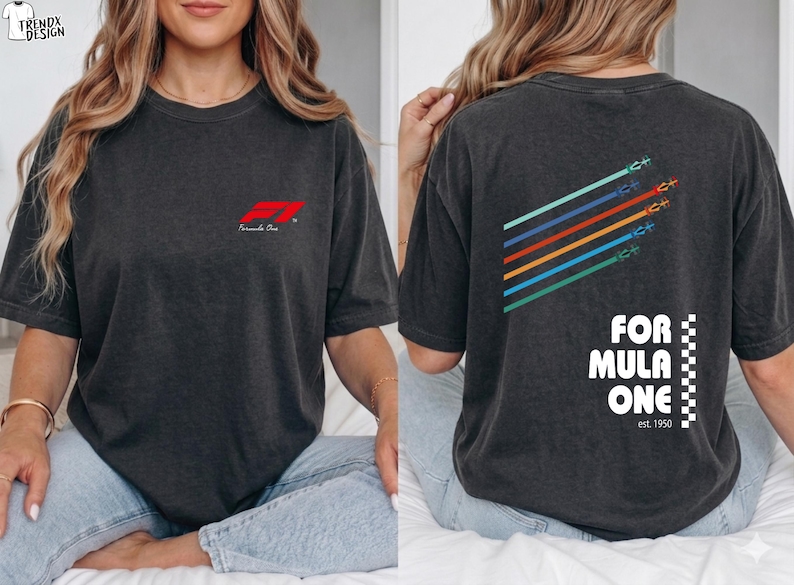 Pu&ograve; includere: Una t-shirt grigio antracite con un piccolo logo rosso Formula One sul petto. Il retro presenta una grafica con cinque linee diagonali colorate con icone di auto da corsa, il testo FORMULA ONE, un motivo a scacchi e la scritta est. 1950.