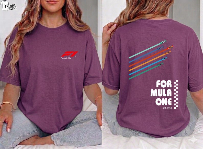 Pu&ograve; includere: Una t-shirt a maniche corte color prugna con un piccolo logo rosso Formula One sul petto. Il retro mostra una grafica di cinque auto da corsa colorate con linee di movimento e il testo Formula One est. 1950 con un bordo a scacchi.