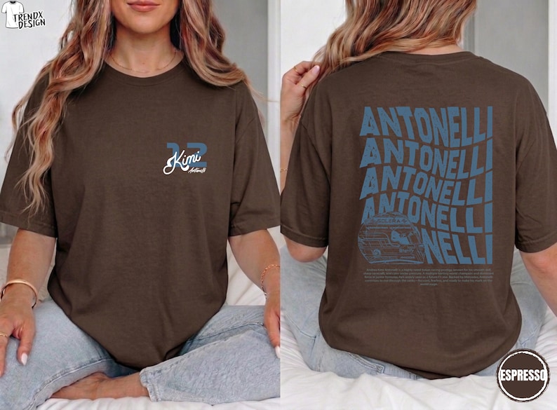 May include: Espresso-coloured t-shirt with blue text and graphics. The front features the number "32" and the name "Kimi" in a script font. The back displays the name "Antinelli" in a wavy design, along with a car graphic.