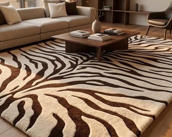 Op de afbeelding: Een rechthoekig vloerkleed met een contrastrijk zebrastrepenpatroon in donkerbruin en crème. Het kleed heeft een dikke, getextureerde pool en bedekt een groot deel van de houten vloer, uitstrekkend van de voorgrond naar het meubilair.