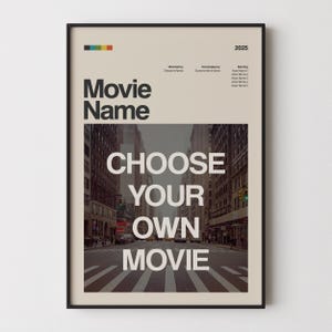 May include: A framed movie poster with a black border. The poster features the words "Movie Name" and "CHOOSE YOUR OWN MOVIE" in large white text. The background is a street scene. The top has a colorful stripe and text.