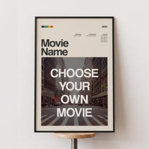 Può includere: Un poster cinematografico incorniciato con un bordo nero. Il poster presenta le parole "Movie Name" e "CHOOSE YOUR OWN MOVIE" in grassetto bianco. Lo sfondo è una scena di strada cittadina. Una striscia colorata è in alto.
