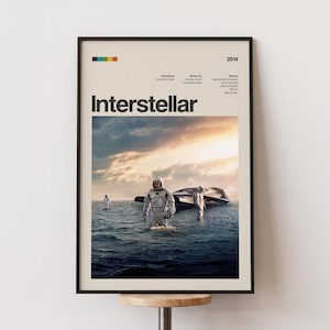 May include: A framed poster for the film "Interstellar" showing astronauts wading through water, with a spaceship in the background. The poster has a black frame and a beige background with the film title.