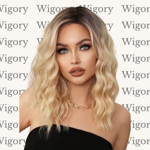 Könnte beinhalten: Eine Frau mit welligem blondem Haar und einer goldenen Halskette. Das Haar hat dunkle Wurzeln und verblasst zu einem helleren Blond. Sie trägt ein schwarzes trägerloses Oberteil. Der Hintergrund wiederholt das Wort "Wigory".