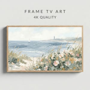 May include: A framed landscape painting depicts a coastal scene with a sailboat on the ocean. The artwork features a lighthouse, beach grass, and pink and white flowers. The text "FRAME TV ART 4K QUALITY" is at the top.