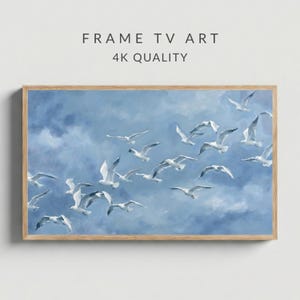 Könnte beinhalten: Ein gerahmtes Kunstwerk mit einer Gruppe weißer Möwen, die vor einem hellblauen Himmel mit Wolken fliegen. Der Text lautet "FRAME TV ART" und "4K QUALITY". Der Rahmen besteht aus hellem Holz.