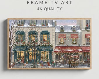 Pode incluir: Impressão de arte digital emoldurada que retrata uma cena de rua europeia nevada com lojas e cafés decorados para as festas. A imagem inclui o texto "FRAME TV ART" e "4K QUALITY". A obra de arte apresenta uma paleta de cores quentes com luzes festivas.