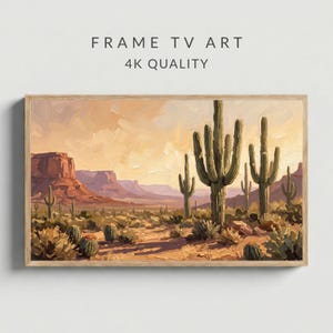 Może przedstawiać: Oprawiony obraz krajobrazu przedstawiający pustynny krajobraz z kaktusami, górami i ciepłą paletą barw. Grafika oznaczona jest jako "FRAME TV ART" i "4K QUALITY". Obraz jest w drewnianej ramie.