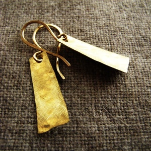 May include: A pair of gold earrings with a hammered texture. The earrings are rectangular in shape and have a simple wire hook closure.