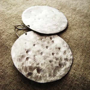 May include: A pair of silver earrings with a hammered texture. The earrings are round and have a slightly irregular shape.