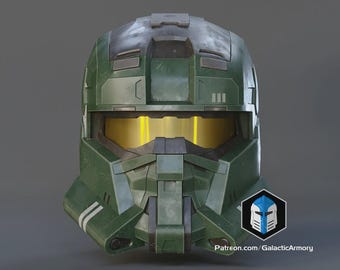 May include: A green and grey military-style helmet with a yellow visor. The helmet features a complex design with panels, vents, and markings. The text "Patreon.com/GalacticArmory" is visible on the lower right.