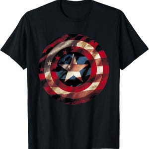 May include: Black t-shirt featuring a distressed graphic of a shield with red and white stripes, a blue center with a white star, and smaller white stars. The design is reminiscent of a patriotic emblem.