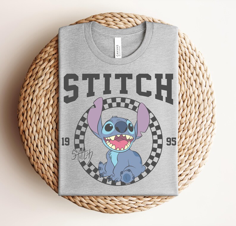 May include: A gray t-shirt featuring the word "STITCH" in dark gray block letters above a cartoon image of Stitch inside a black and white checkered circle. The numbers "19" and "95" flank the image.