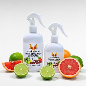 May include: Two white plastic spray bottles of Citrus Sabotage Castile Multi-Surface Cleaning Spray, one 16.9 fl oz and one 10.1 fl oz, surrounded by fresh lime halves and grapefruit slices on a white background.