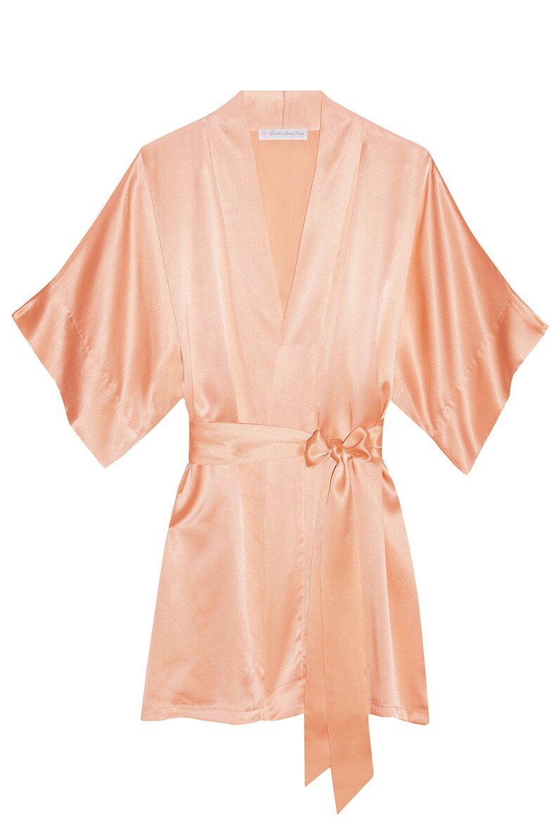 May include: A peach-colored satin robe with a self-tie sash. The robe has a V-neck and short sleeves.