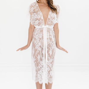 May include: A white lace robe with a deep V-neckline and short sleeves. The robe is tied at the waist with a satin ribbon.