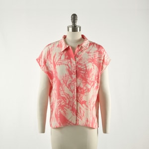 Könnte beinhalten: Ein rosa-weiß gemustertes, kurzärmeliges Hemd mit Knöpfen und Kragen.