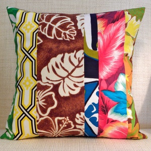 May include: A colorful patchwork pillow cover with a tropical theme. The cover features a variety of floral and leaf patterns in shades of green, brown, yellow, pink, blue, and white.