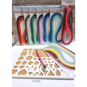 May include: A craft supplies set featuring colorful quilling paper strips, a pink quilling tool, and a white template with various shapes. The set includes multiple packs of quilling paper in different color combinations, perfect for paper art projects.