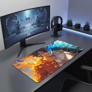 Op de afbeelding: Een rechthoekige gaming muismat met een levendige anime-stijl illustratie. Het ontwerp toont een personage verdeeld tussen vurige oranje en ijsblauwe elementen. De muismat ligt op een grijze bureau, met een monitor en koptelefoon op de achtergrond.