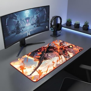 Peut inclure: Tapis de souris rectangulaire pour le jeu, avec une illustration vibrante de style anime représentant un personnage en flammes. Le tapis a une bordure rouge et est posé sur un bureau gris, avec un écran d'ordinateur et un casque.