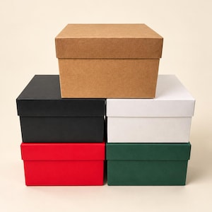 May include: A stack of five rectangular gift boxes with lids. The top box is brown kraft paper. Below it, on the left, is a black box, and on the right is a white box. The bottom row features a red box on the left and a dark green box on the right.