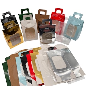 May include: A selection of colourful gift boxes with clear window panels and handles. The boxes are in various colours, including gold, silver, red, blue, green, and brown. Some boxes are assembled, while others are flat.