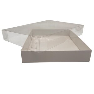 May include: A clear, rectangular box with a transparent lid, partially open to reveal the white interior. The lid has small, curved cutouts on the sides. The box is designed for packaging and display.