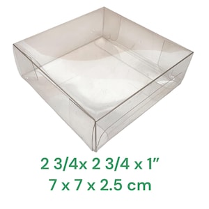 May include: A transparent, square plastic container with gently sloping sides. The dimensions are 7 x 7 x 2.5 cm. The container is empty and is set against a white backdrop. The text "2 3/4x 2 3/4 x 1" and "7 x 7 x 2.5 cm" is printed below the container.