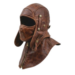 May include: A brown leather aviator-style headgear featuring a full-face mask with ventilation eyelets, side ear flaps with brass-toned snap buttons, and a front zipper closure that extends down to cover the neck area with a textured finish.