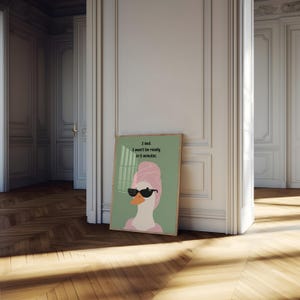 Puede incluir: Un cuadro enmarcado con un dibujo de un ganso con gafas de sol y una toalla rosa. El fondo es verde claro y el texto dice: &laquo;Ment&iacute;. No estar&eacute; listo en 5 minutos.&raquo;