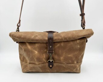 Bolso bandolera de lona encerada color tostado con correa de cuero.
