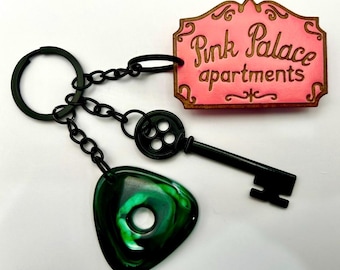 Coraline inspired pink palace keychain with black button skeleton key and green seeing stone