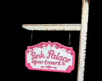 Pink palace sign with stand.