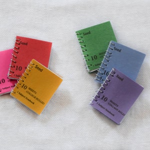 May include: Five small spiral bound notebooks with colorful covers. Each notebook has the word "Seed" printed on the cover and the text "10 Sheets College Ruled 1 Subject Notebook".