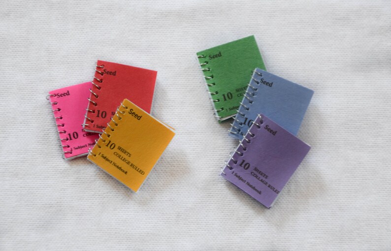 May include: Five small spiral bound notebooks with colorful covers. Each notebook has the word "Seed" printed on the cover and the text "10 Sheets College Ruled 1 Subject Notebook".
