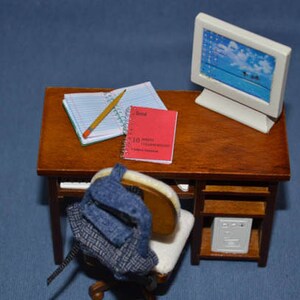May include: A miniature wooden desk with a computer monitor, a pencil, two notebooks, and a backpack. The desk has a shelf underneath with a small white box.