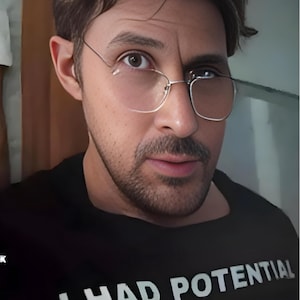 May include: A black t-shirt with the text "I HAD POTENTIAL" in white block letters. The person in the image is wearing thin-framed glasses.