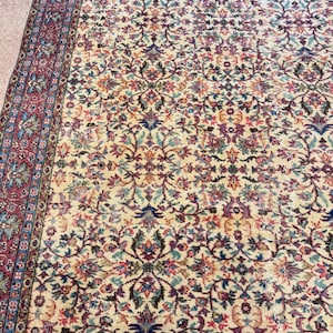 May include: A vintage area rug with an intricate floral pattern in cream, burgundy, blue, and green. The rug features a detailed border and a central design of stylized flowers and vines, creating a classic, ornate look.