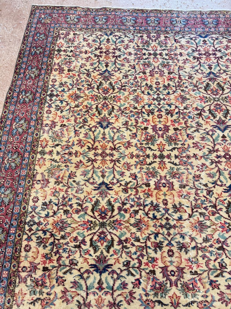 May include: A vintage area rug with an intricate floral pattern in cream, burgundy, blue, and green. The rug features a detailed border and a central design of stylized flowers and vines, creating a classic, ornate look.