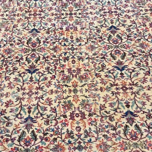 May include: An antique beige rug with an intricate floral pattern in shades of blue, pink, and green. The rug features a detailed, symmetrical design with a distressed appearance, suggesting age and use. The rug's style is reminiscent of traditional Persian or Oriental rugs.