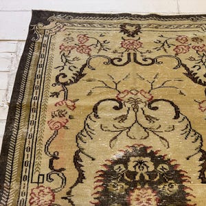 May include: An antique rug with a beige field and a dark brown border. The rug features a floral pattern in shades of red and brown, with intricate details and a distressed appearance. The rug is rectangular and appears to be made of woven material.