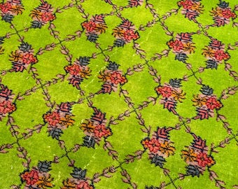 May include: A vibrant lime green rug featuring a repeating diamond lattice pattern. Each intersection of the dark brown grid is adorned with a small, multi-colored floral motif in shades of red, orange, and dark gray, creating a structured design.