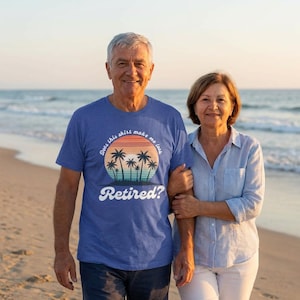 May include: A blue t-shirt with the text "Does this shirt make me look Retired?" in white. The shirt features a sunset design with palm trees. The image shows a couple on a beach.