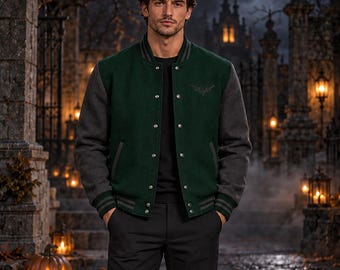 May include: A varsity jacket featuring a dark green wool-blend body and charcoal gray sleeves. The jacket has a snap-button front closure, ribbed cuffs with gray stripes, and a small embroidered emblem on the left chest, worn over a black shirt.