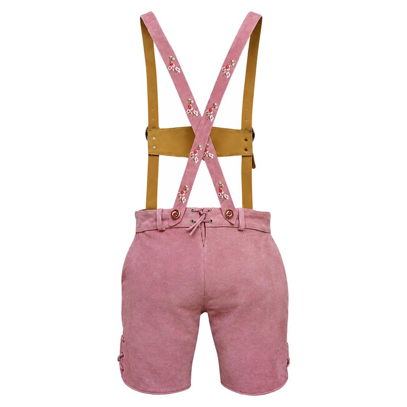 Puede incluir: Pantalones cortos de lederhosen de ante rosa con tirantes de cuero marr&oacute;n. Los tirantes se cruzan en la espalda y est&aacute;n decorados con flores bordadas. Los pantalones cortos tienen una parte delantera con cordones y detalles laterales decorativos.